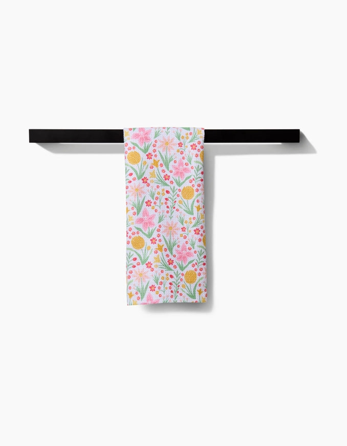 Floral-patterned towel hanging on a black rod against a white background