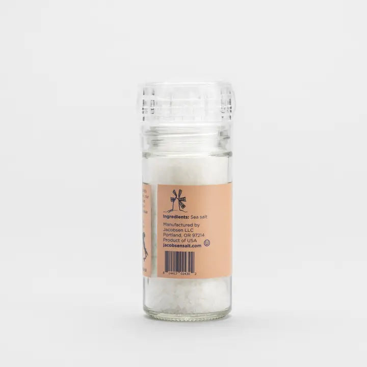 Glass salt shaker with a label on a white background