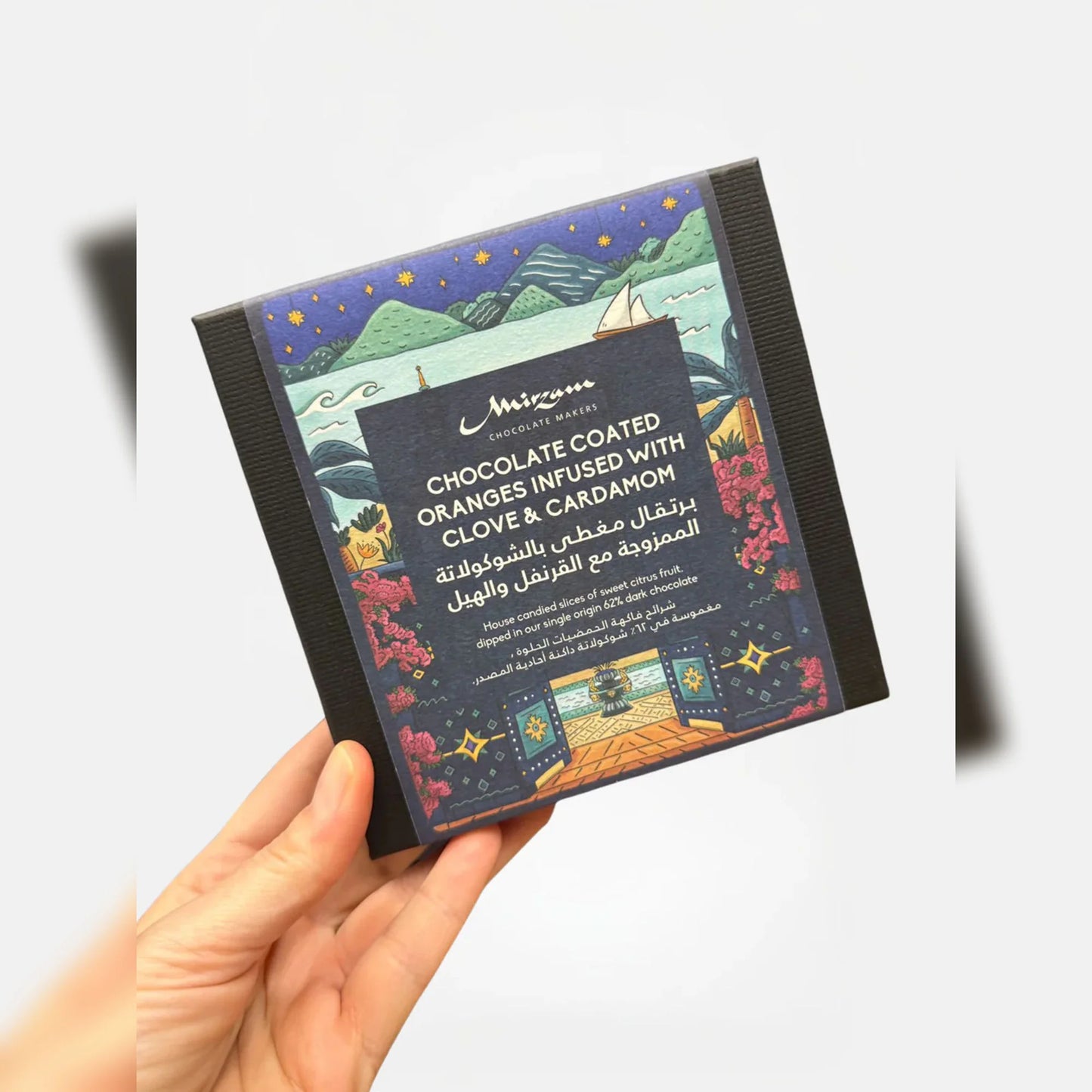 Hand holding a chocolate packaging with a colorful design and text.