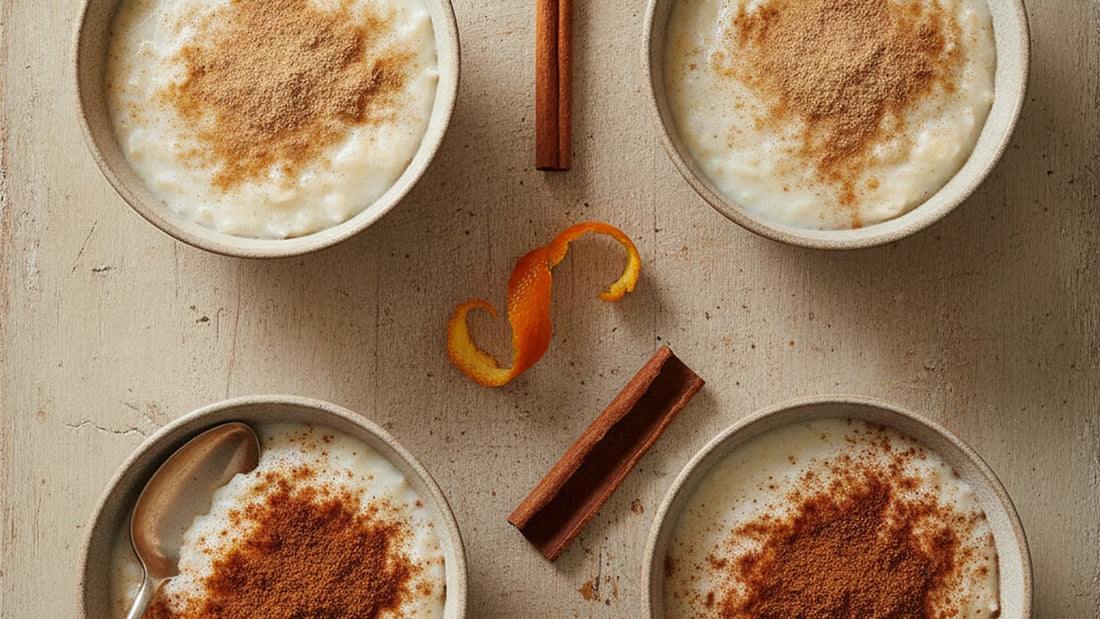 Four small bowls of creamy rice pudding, two dusted pale tan with Ceylon cinnamon and two dusted darker red-brown with cassia, a thin papery cinnamon quill resting on the table beside them