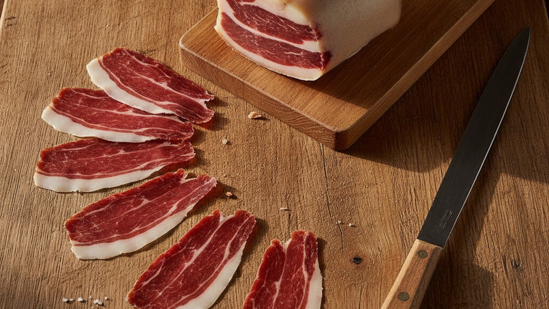 Thin, translucent slices of jamón ibérico fanned across a wooden board, the fat marbled and glossy, with tiny white specks visible in the lean, beside a partly carved leg on its stand
