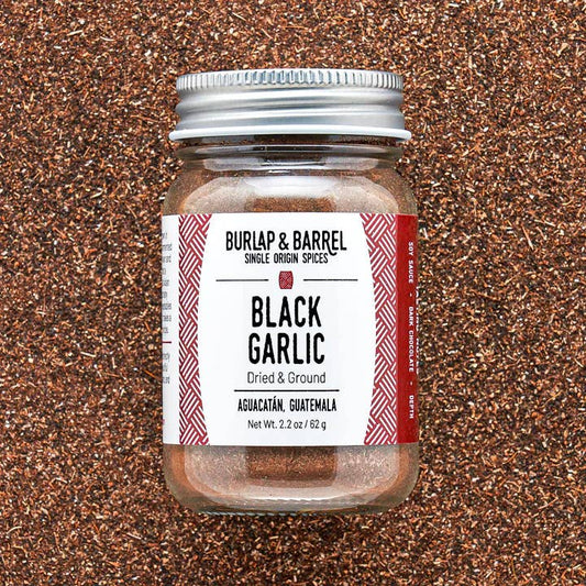 Jar of Burlap & Barrel Black Garlic on a textured brown background