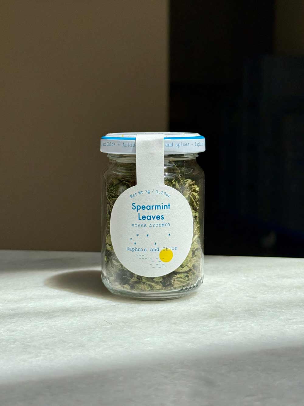 Jar of spearmint leaves with a label on a gray surface