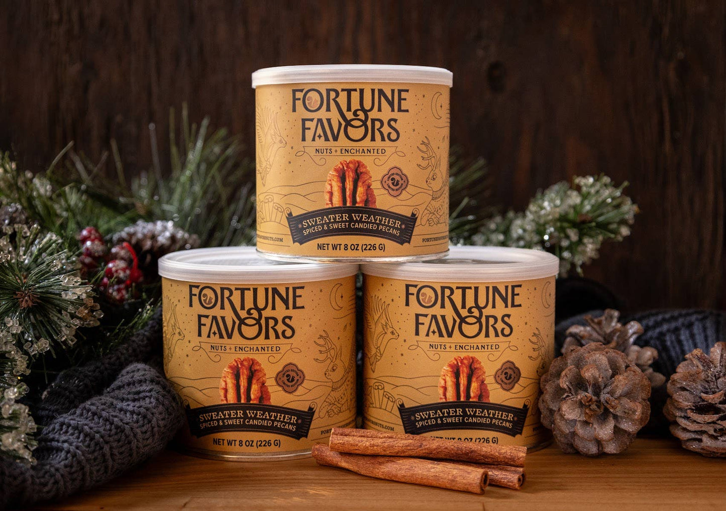 Three cans of 'Fortune Favors' candy canes on a wooden surface with decorative elements.