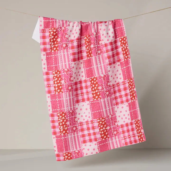 Pink and orange patchwork towel hanging on a line against a neutral background