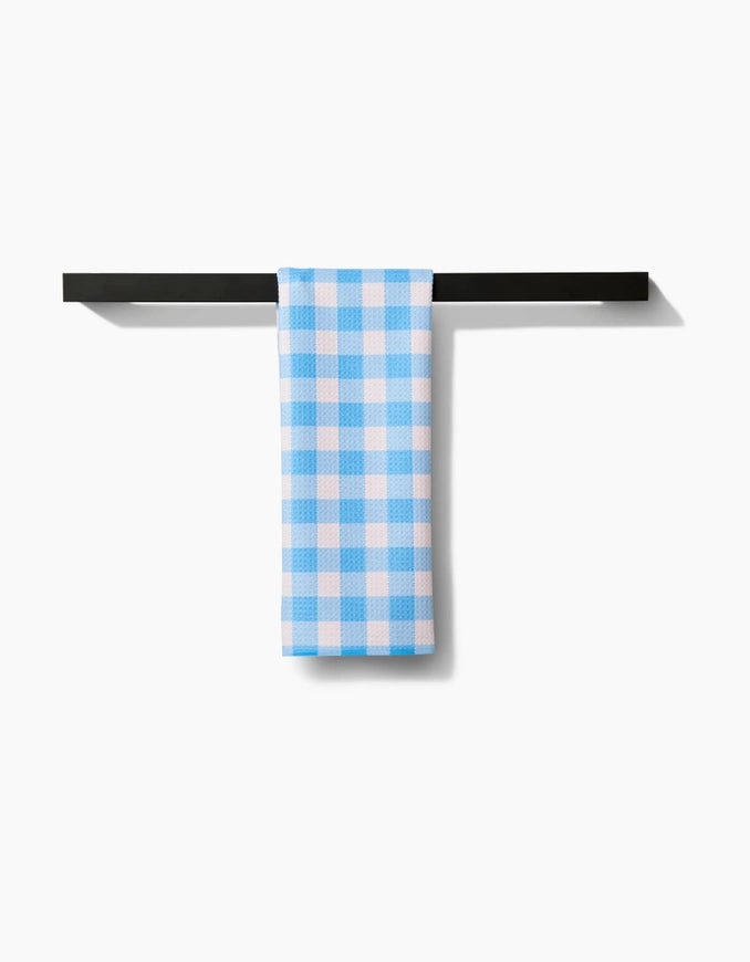 Blue and white checkered towel hanging on a black metal rack against a white background