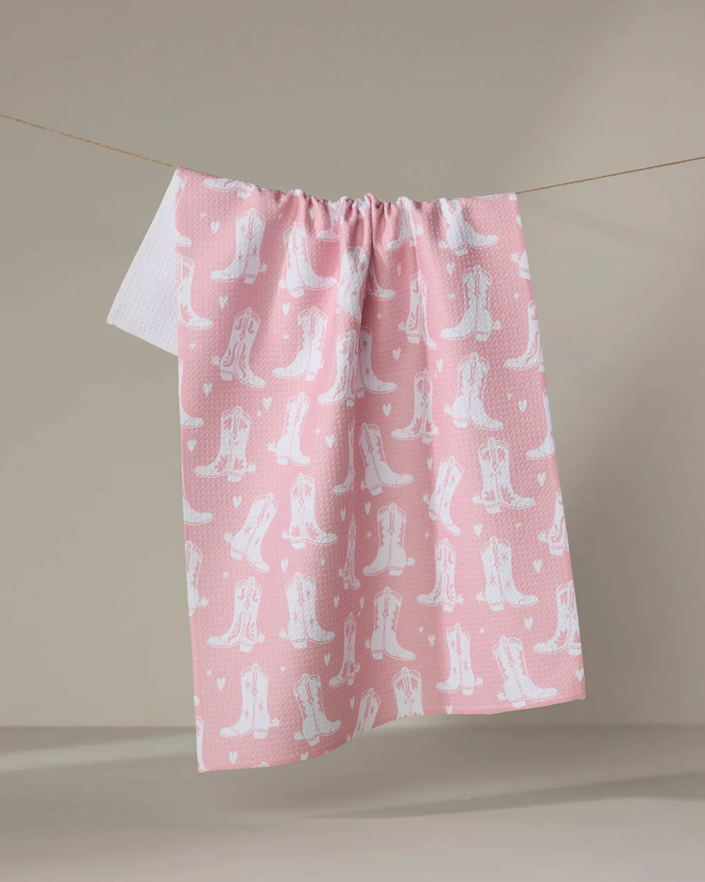 Pink fabric with white cowboy boot pattern on a beige background