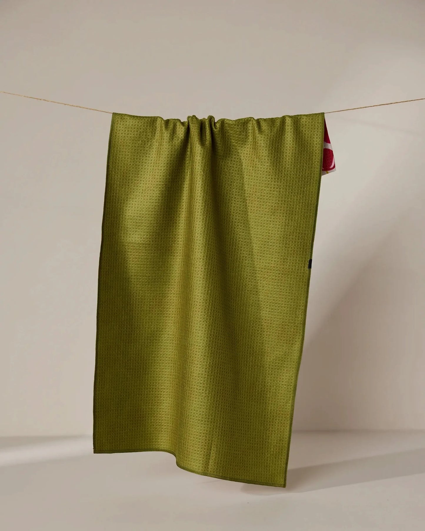 Green fabric hanging on a clothesline against a beige background