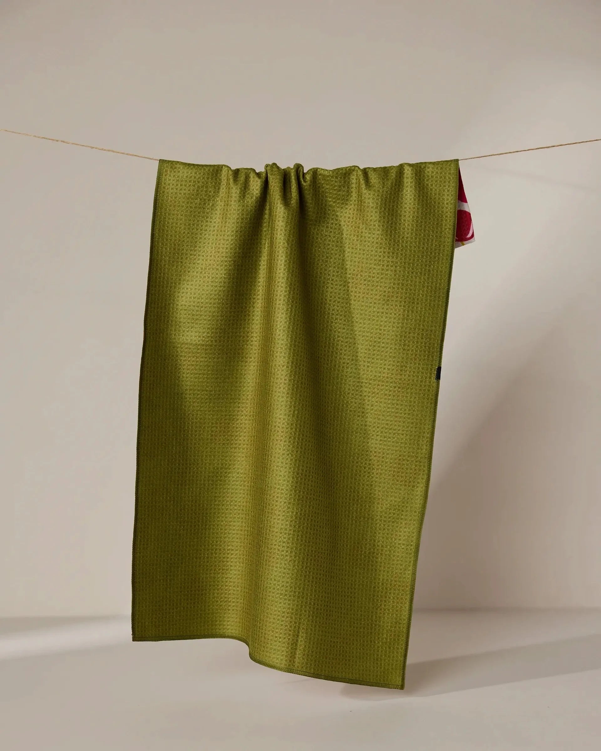 Green fabric hanging on a clothesline against a beige background