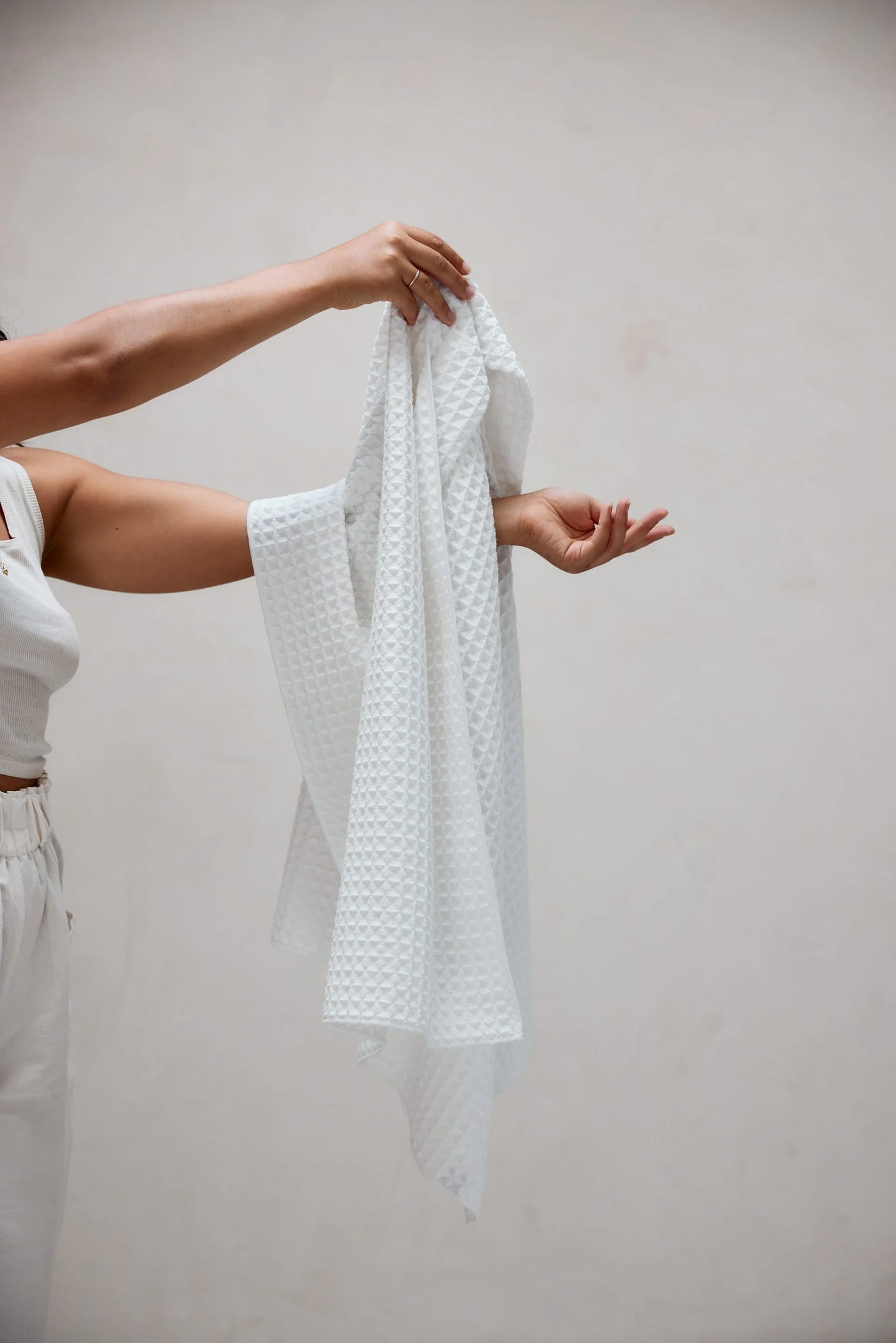 Person holding a white textured fabric against a plain background