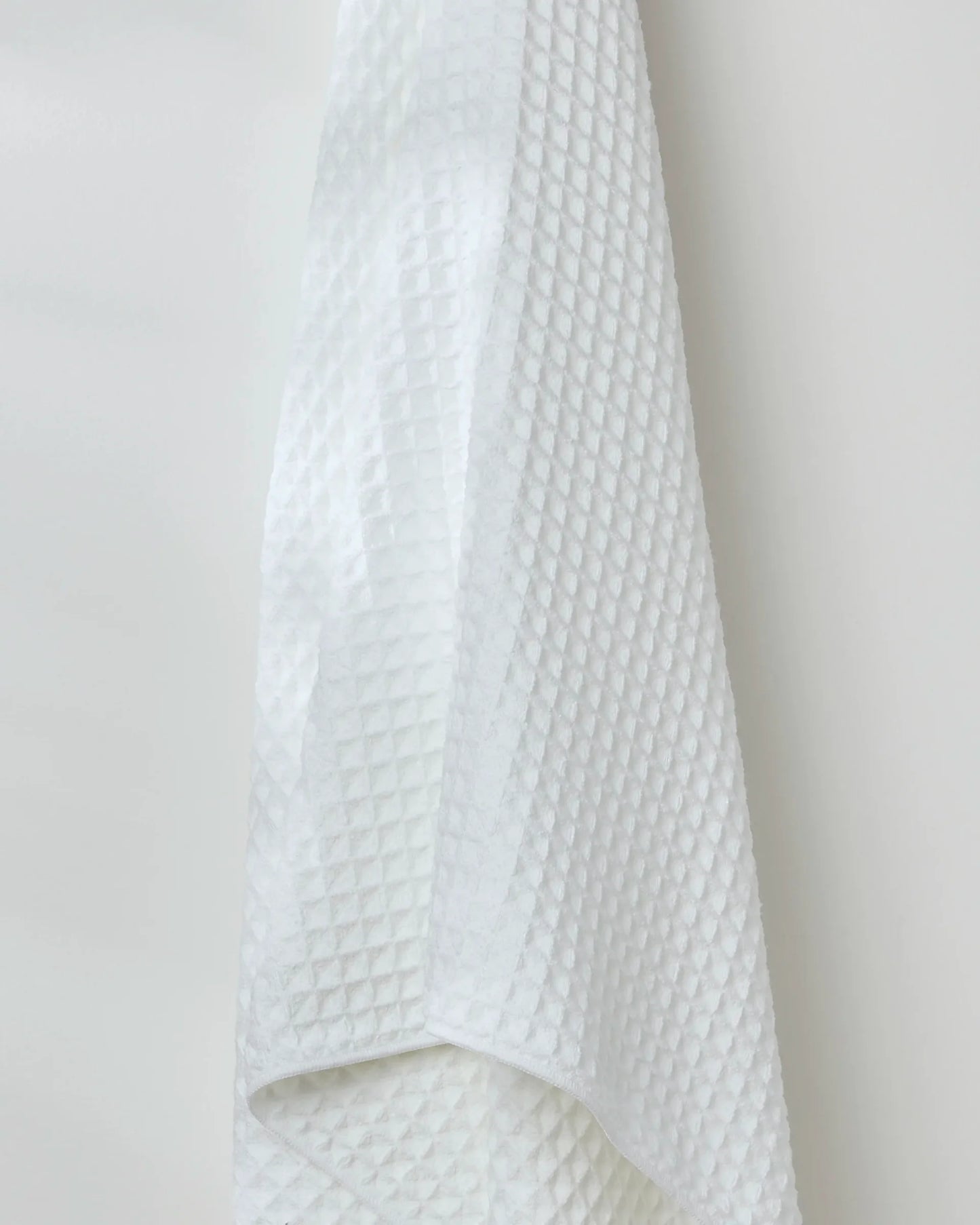 White textured towel hanging against a plain background