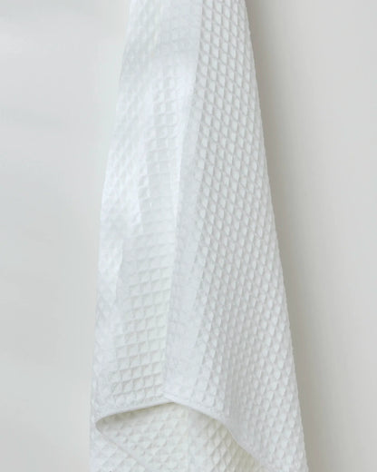 White textured towel hanging against a plain background