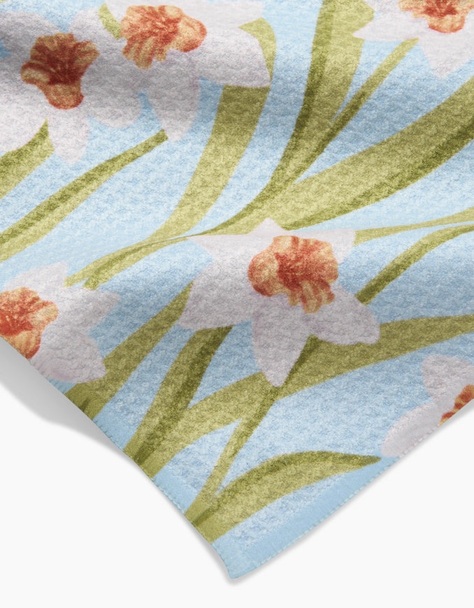 Floral patterned rug with white flowers and green leaves on a light blue background