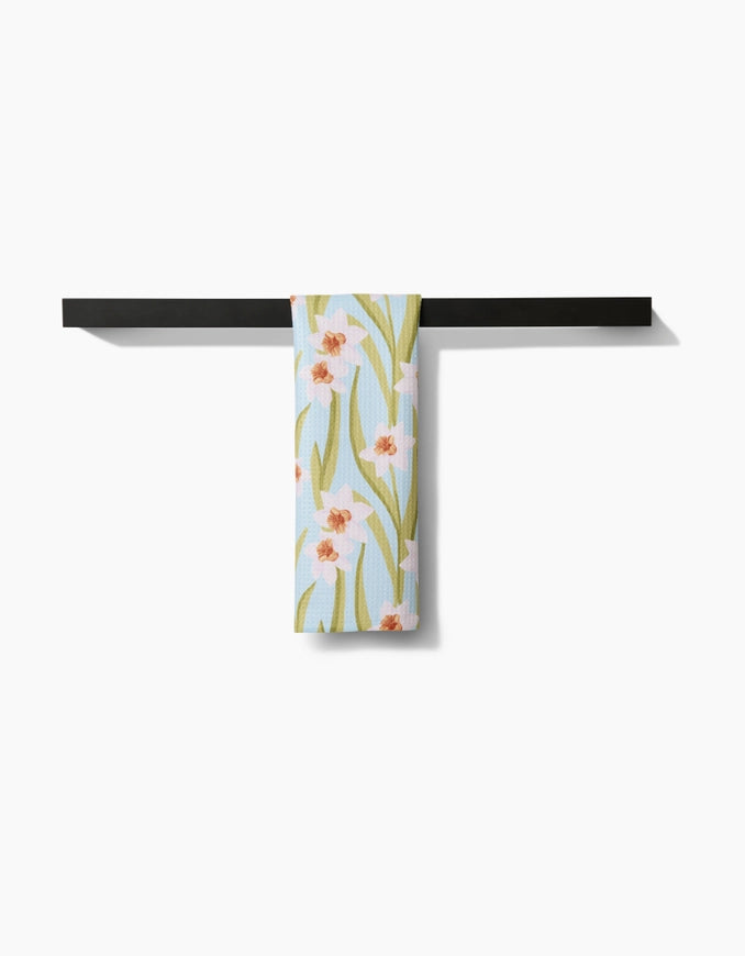 Floral-patterned towel hanging on a black metal rack against a white background