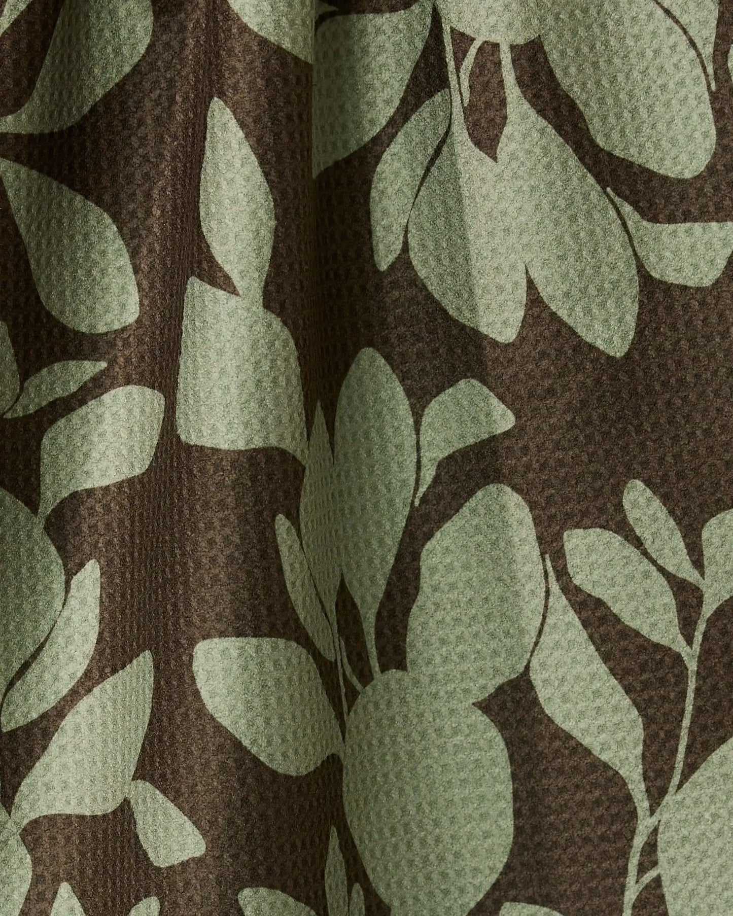 Fabric with green leaf pattern on brown background
