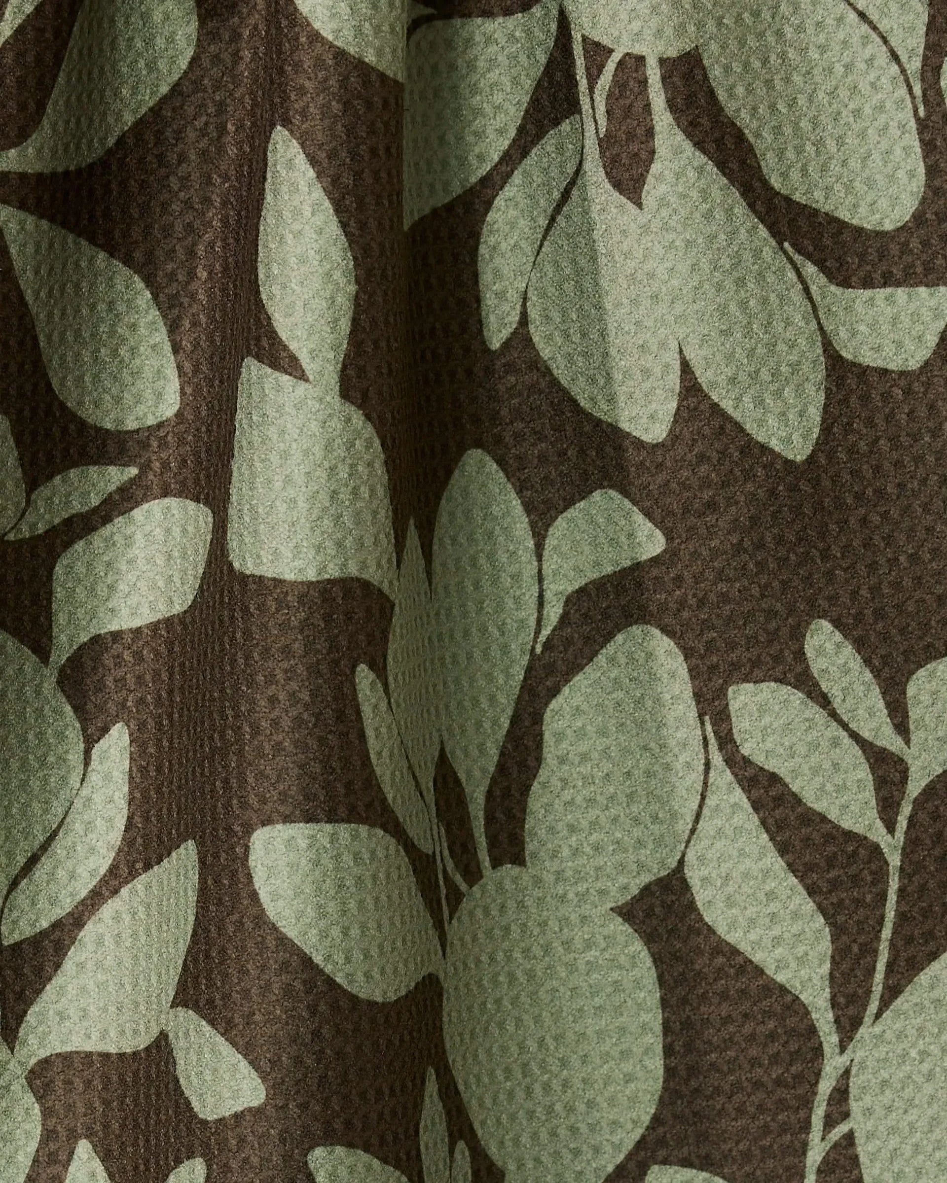 Fabric with green leaf pattern on brown background