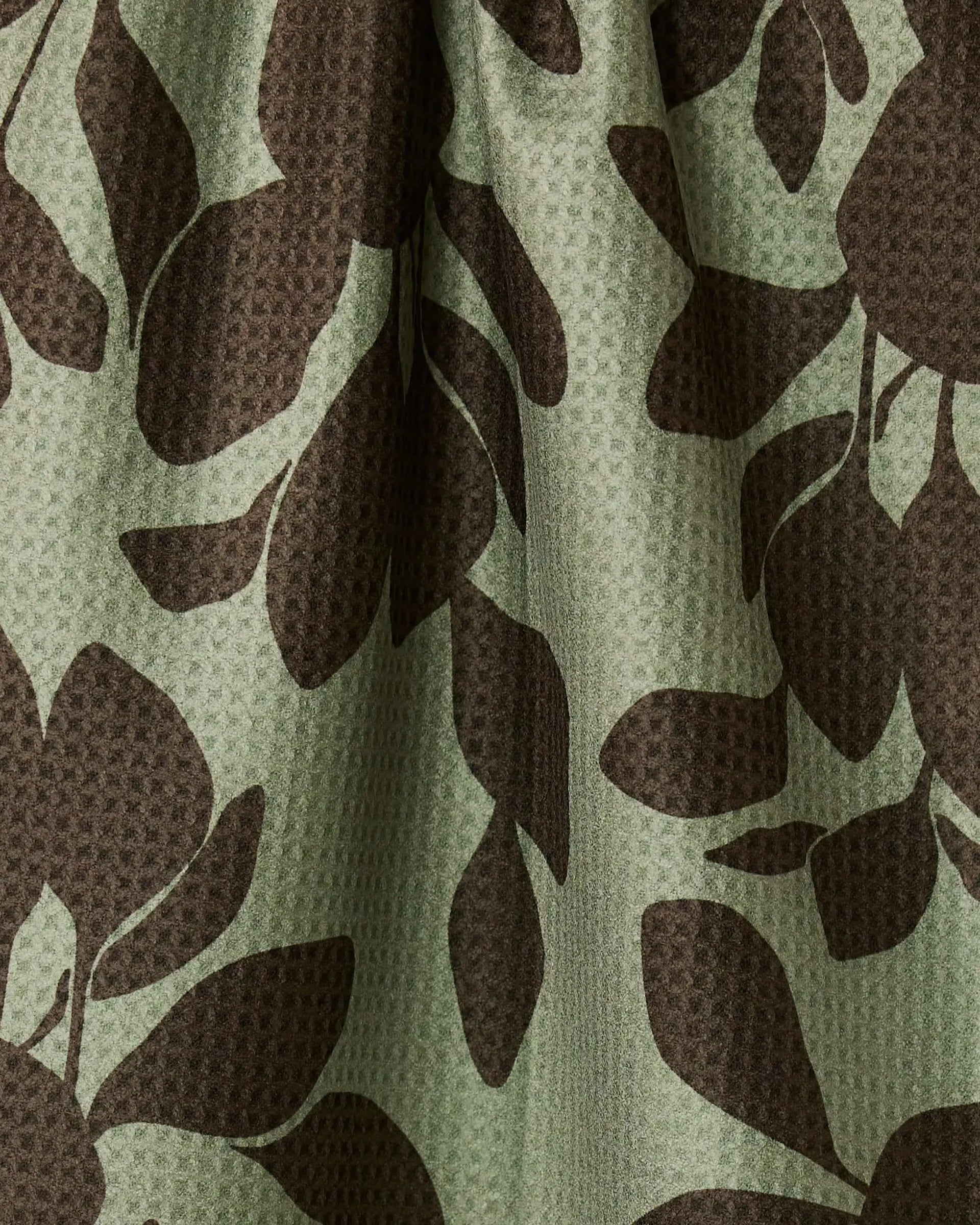 Close-up of a fabric with brown leaf pattern on a green background