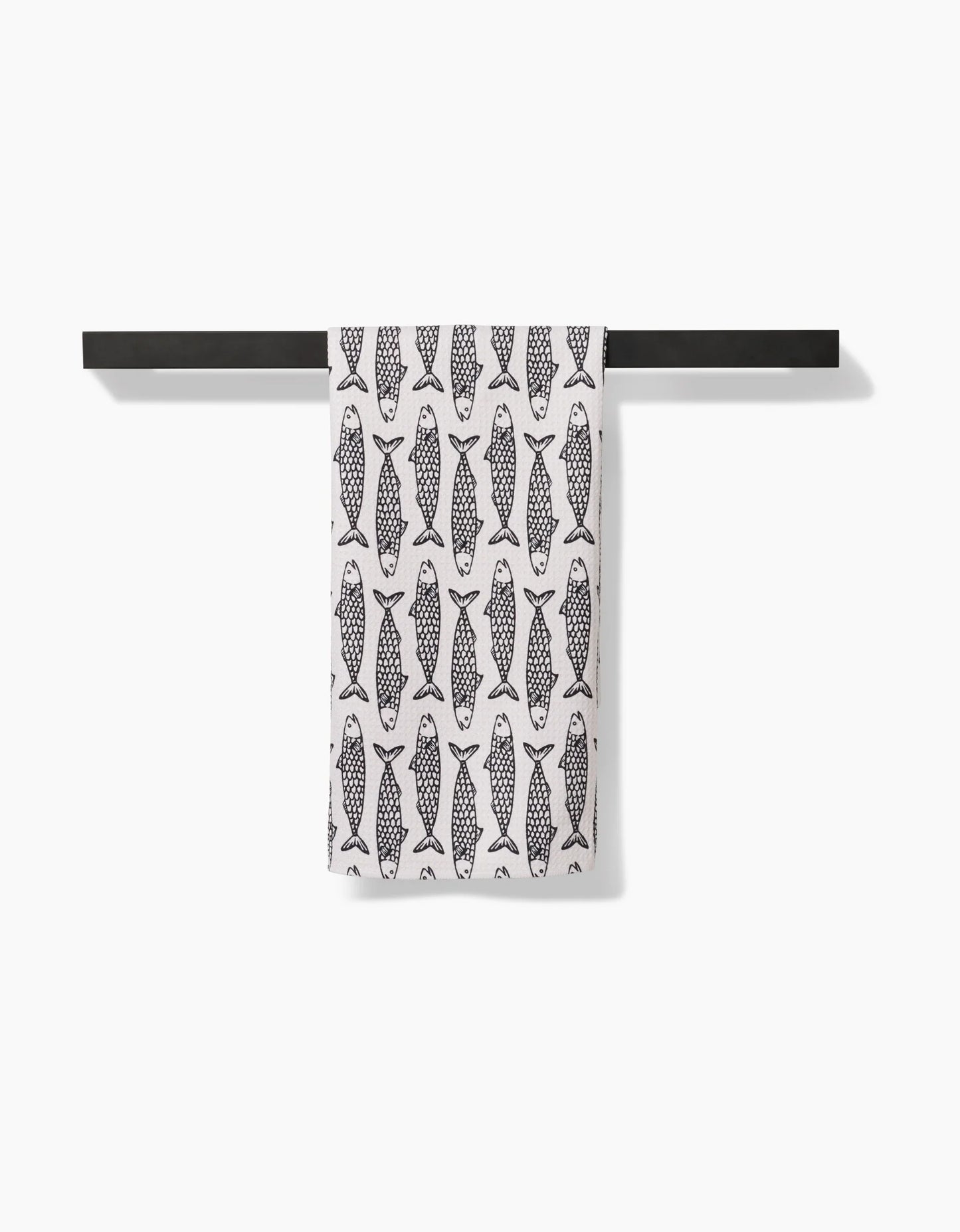 Towel with fish pattern hanging on a black rod against a white background
