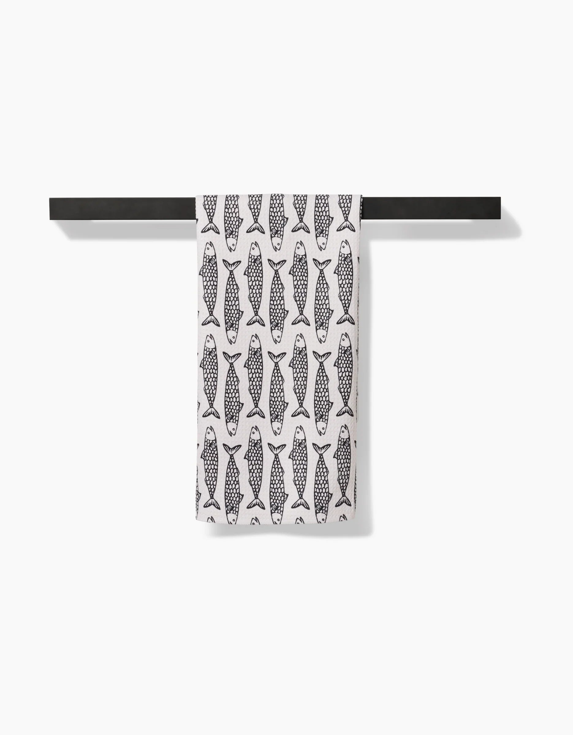 Towel with fish pattern hanging on a black rod against a white background