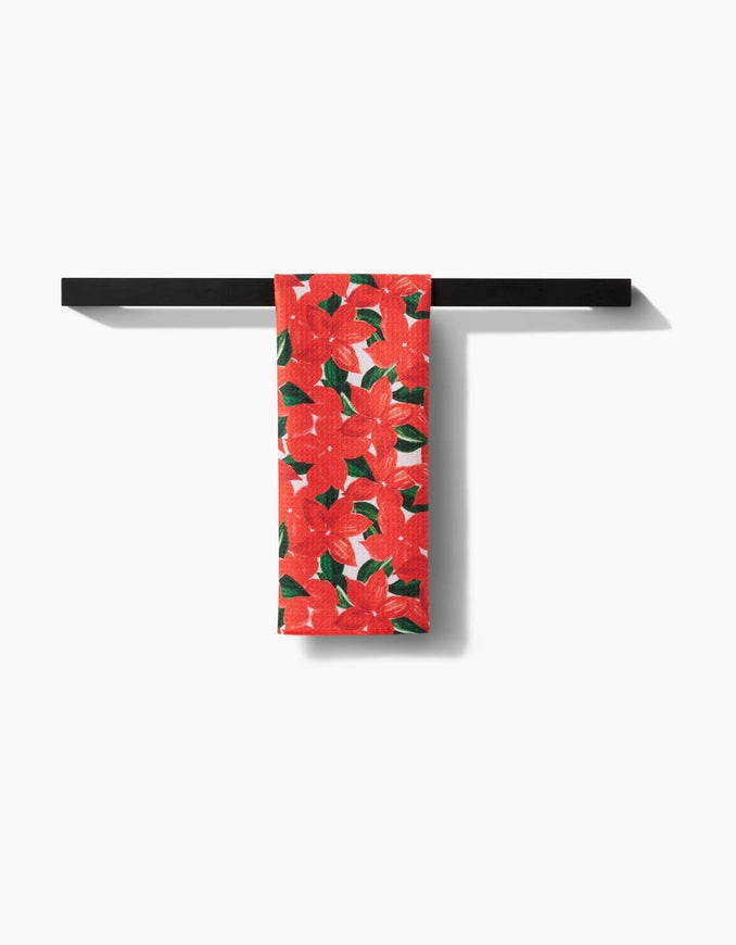 Red towel with green leaf pattern hanging on a black towel rack against a white background