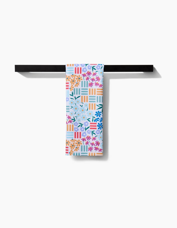 Colorful patterned towel hanging on a black metal rack against a white background