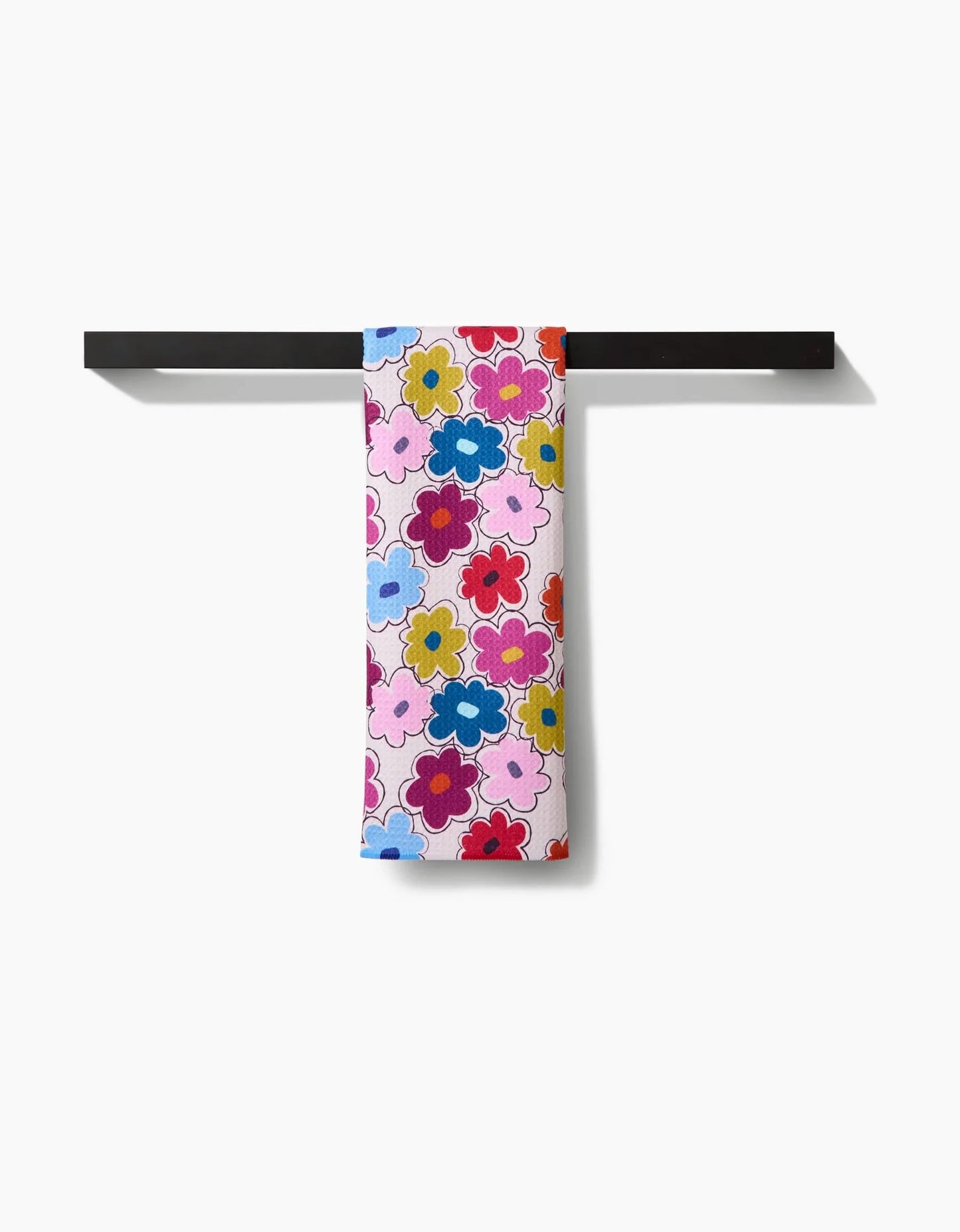 Colorful floral towel hanging on a black metal rack against a white background