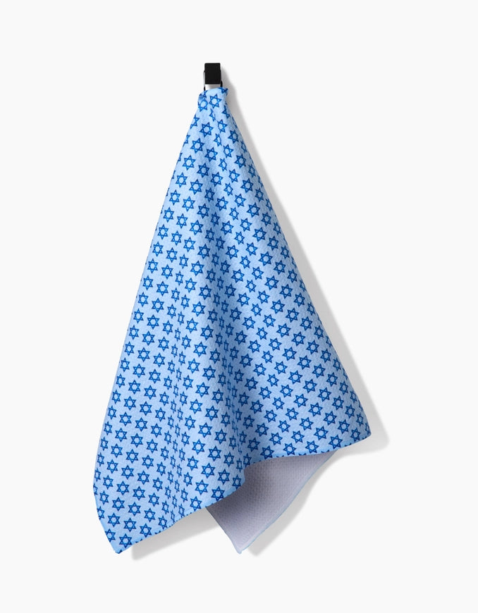 Blue star-patterned towel hanging on a black clip against a white background