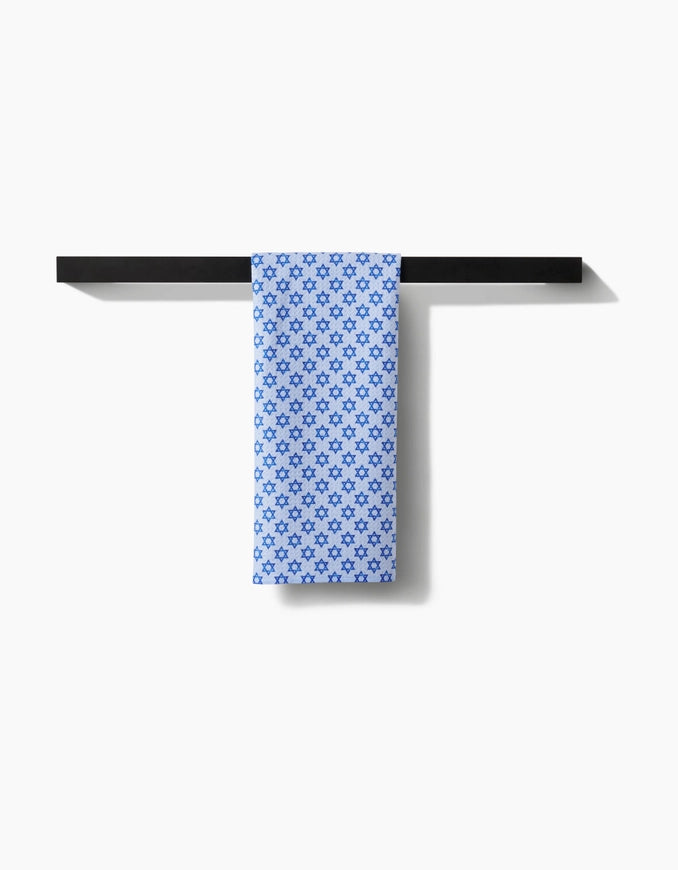 Blue patterned towel hanging on a black towel rack against a white background