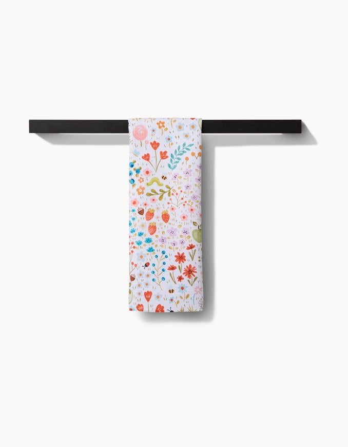 Floral-patterned towel hanging on a black metal rack against a white background