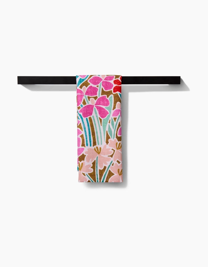 Floral-patterned towel hanging on a black rack against a white background