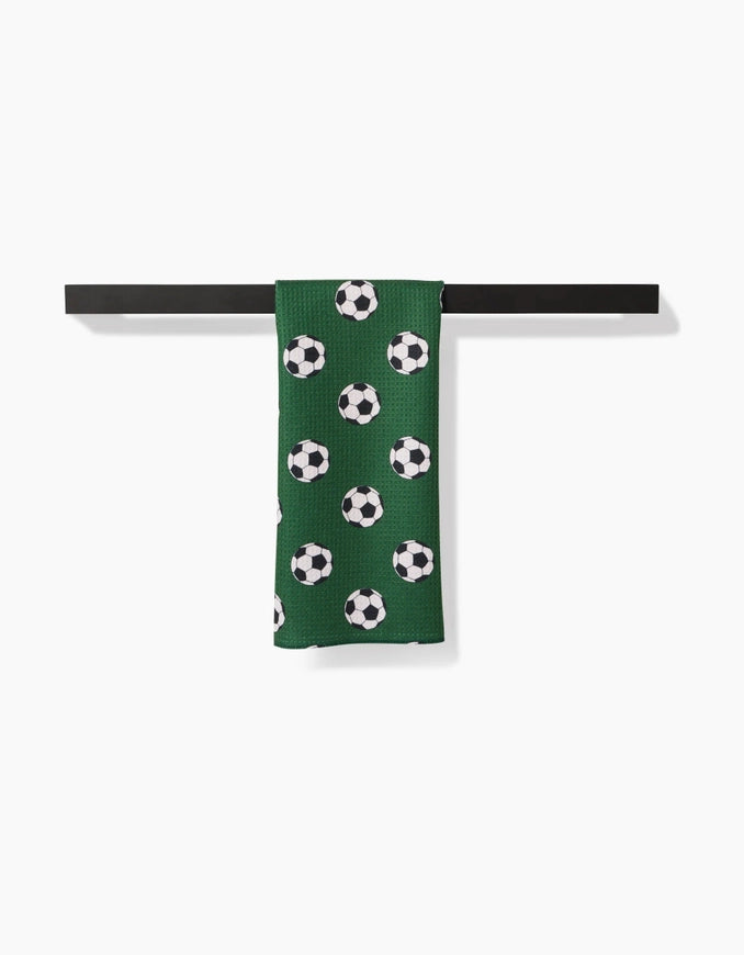 Green sock with soccer ball pattern on a black bar against a white background