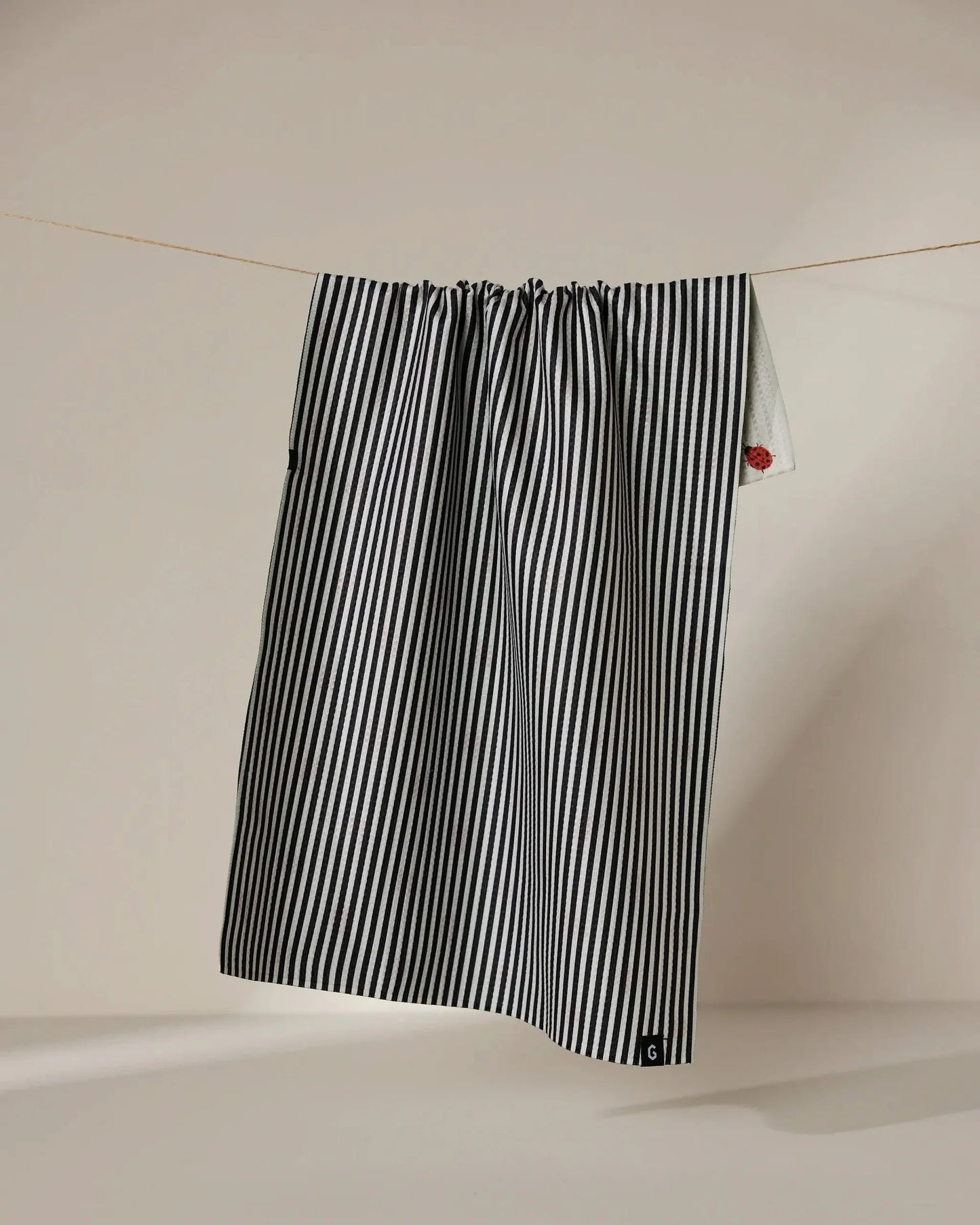 Black and white striped towel hanging on a line against a beige background
