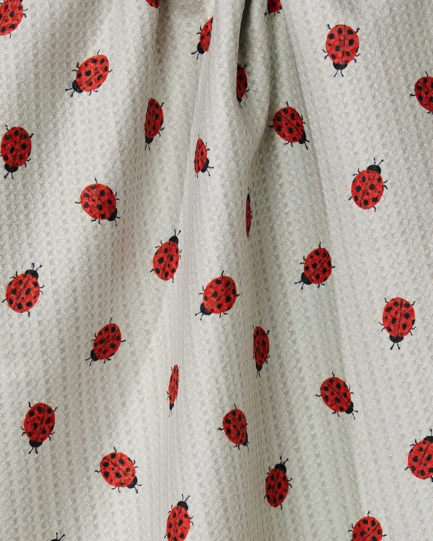 Fabric with red and black ladybug pattern on a beige background