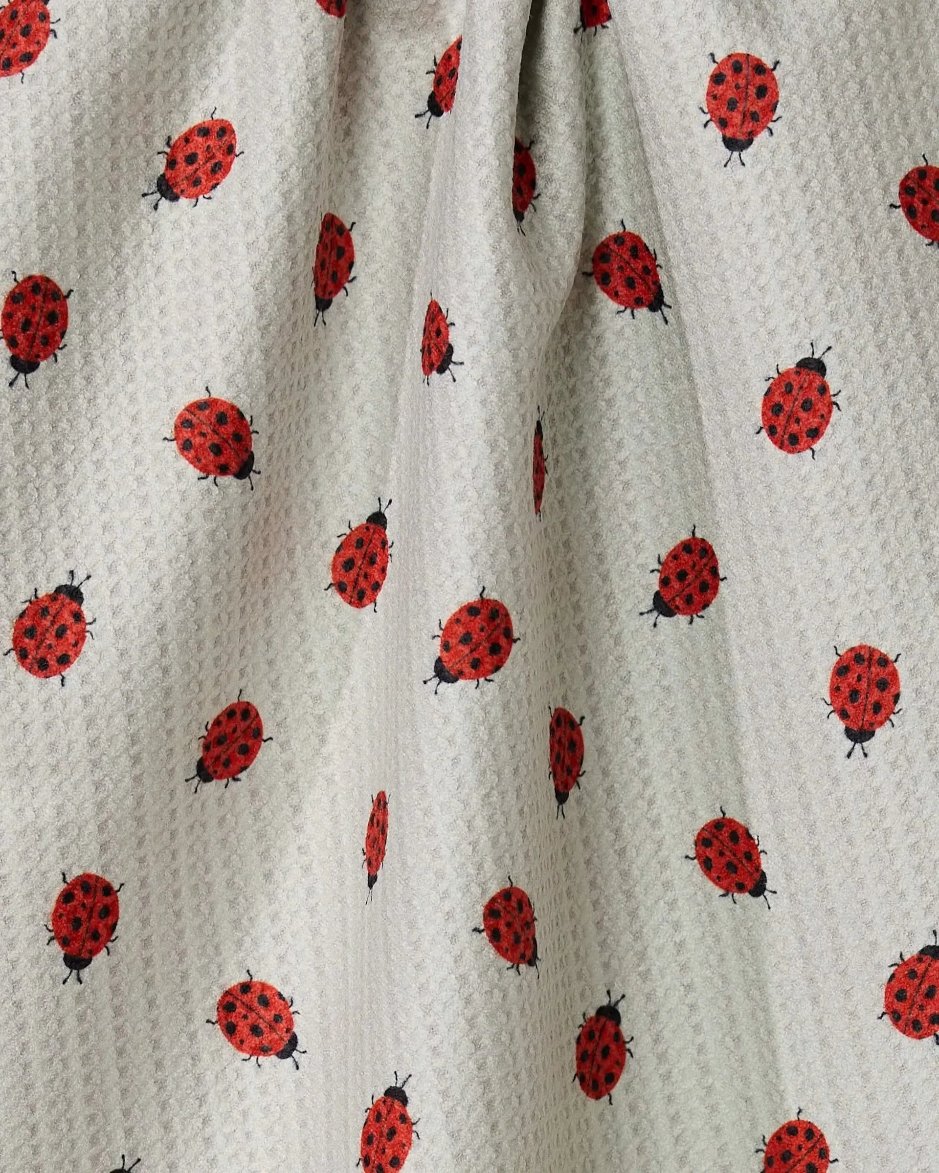 Fabric with red and black ladybug pattern on a beige background