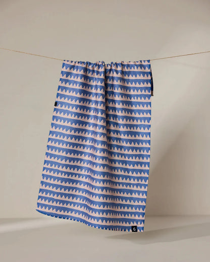 Blue and white patterned towel hanging on a line against a plain background