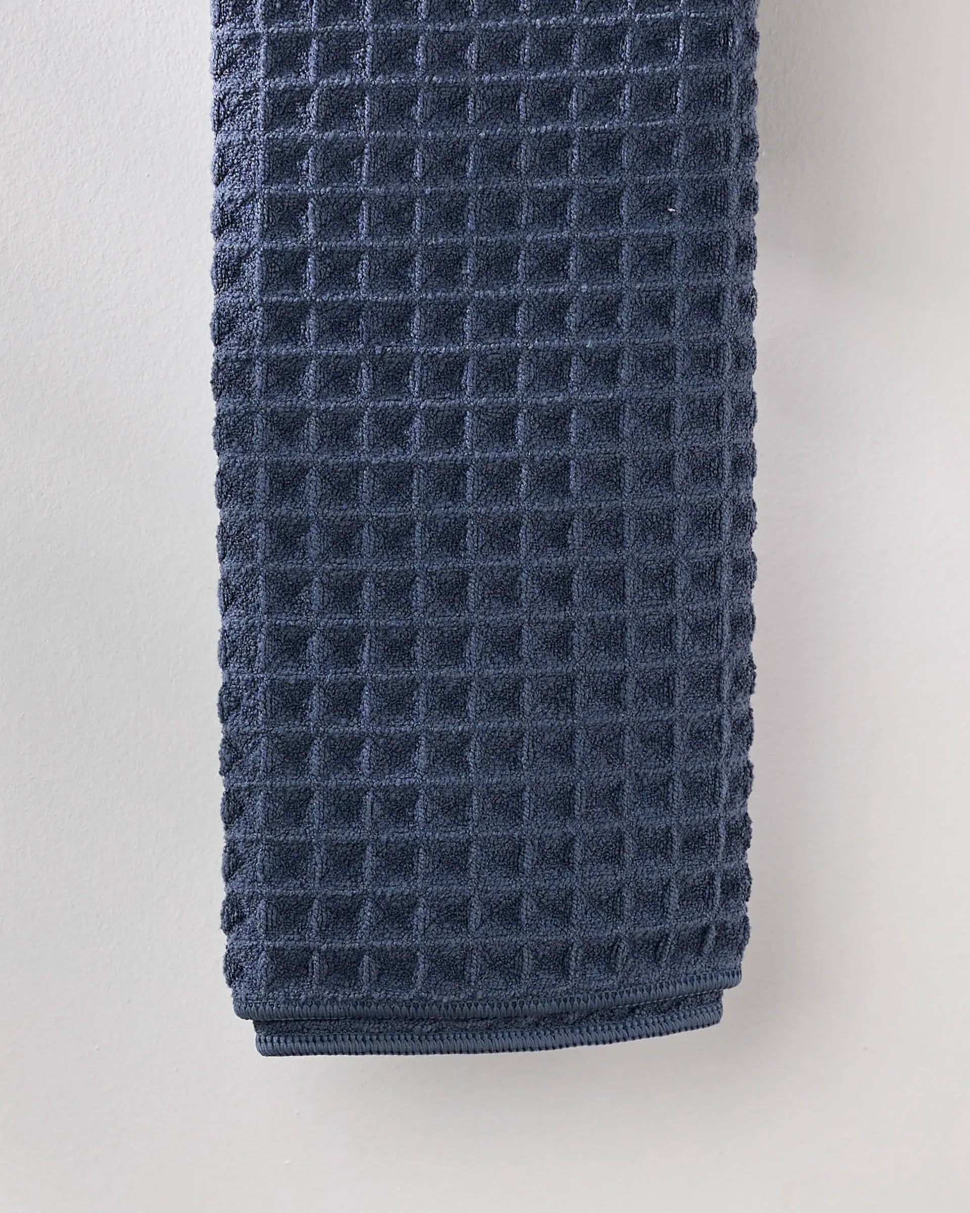 Folded blue textured towel on a light gray background