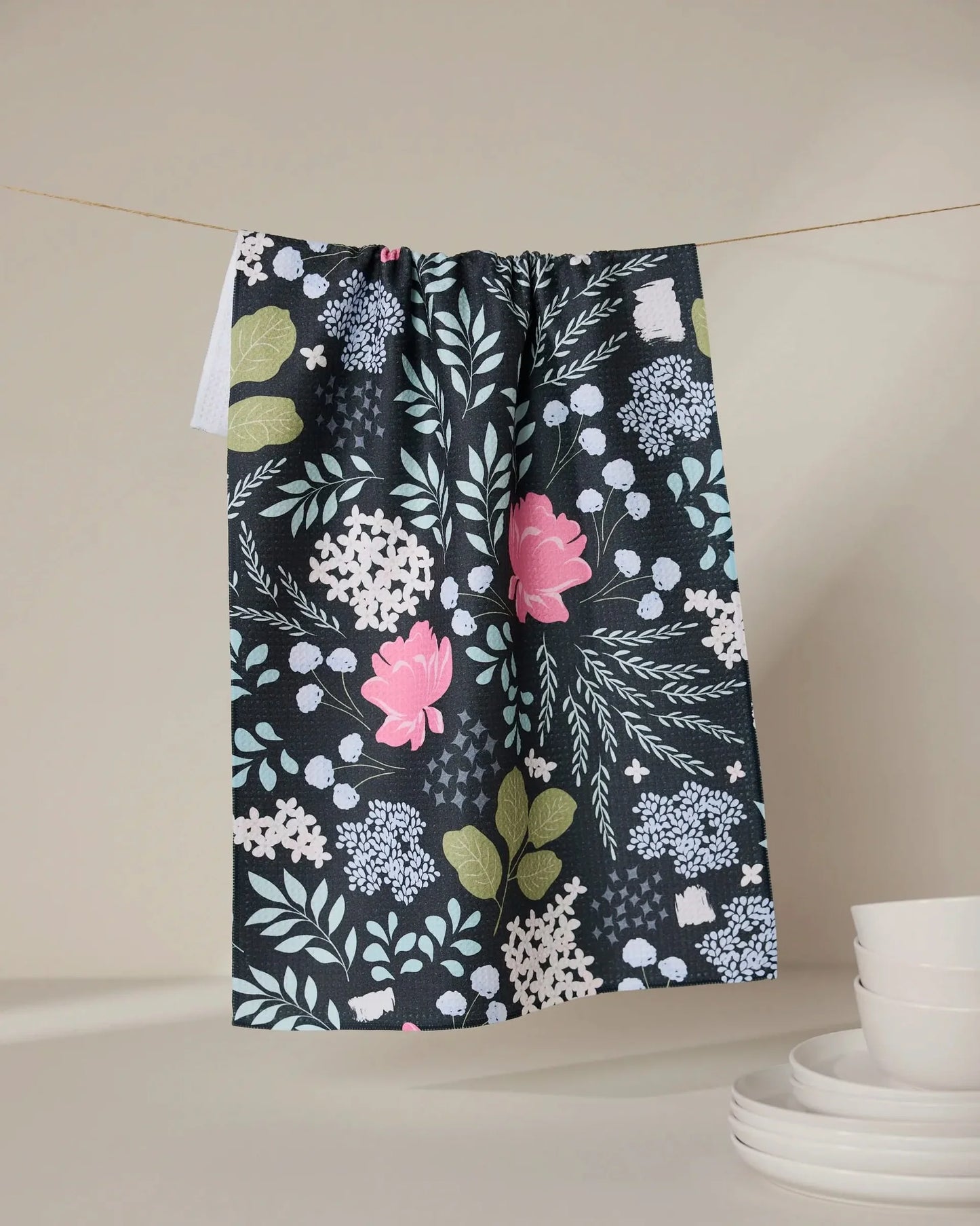 Floral patterned towel hanging on a line with a neutral background