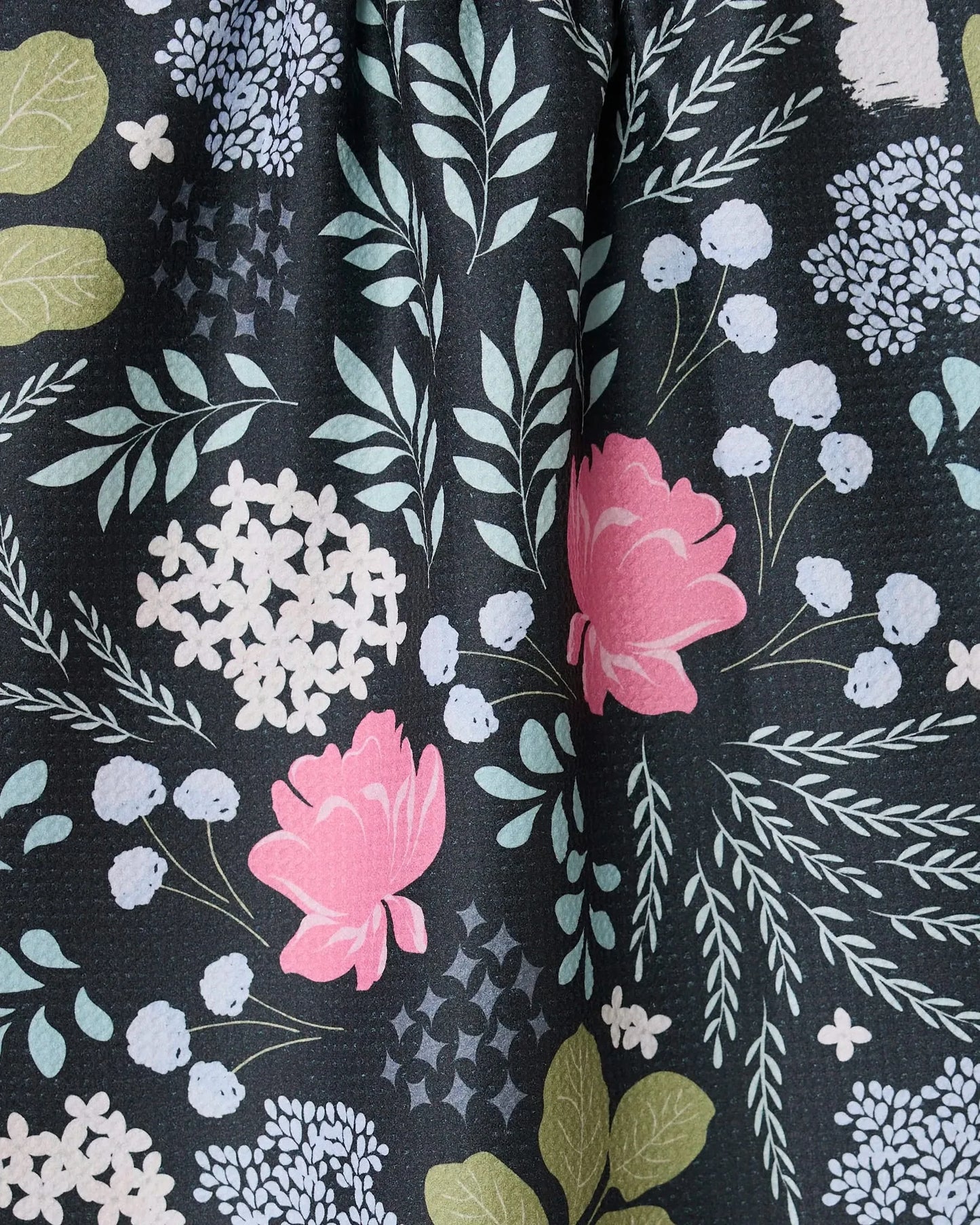 Close-up of floral fabric with pink flowers and green leaves on a dark background