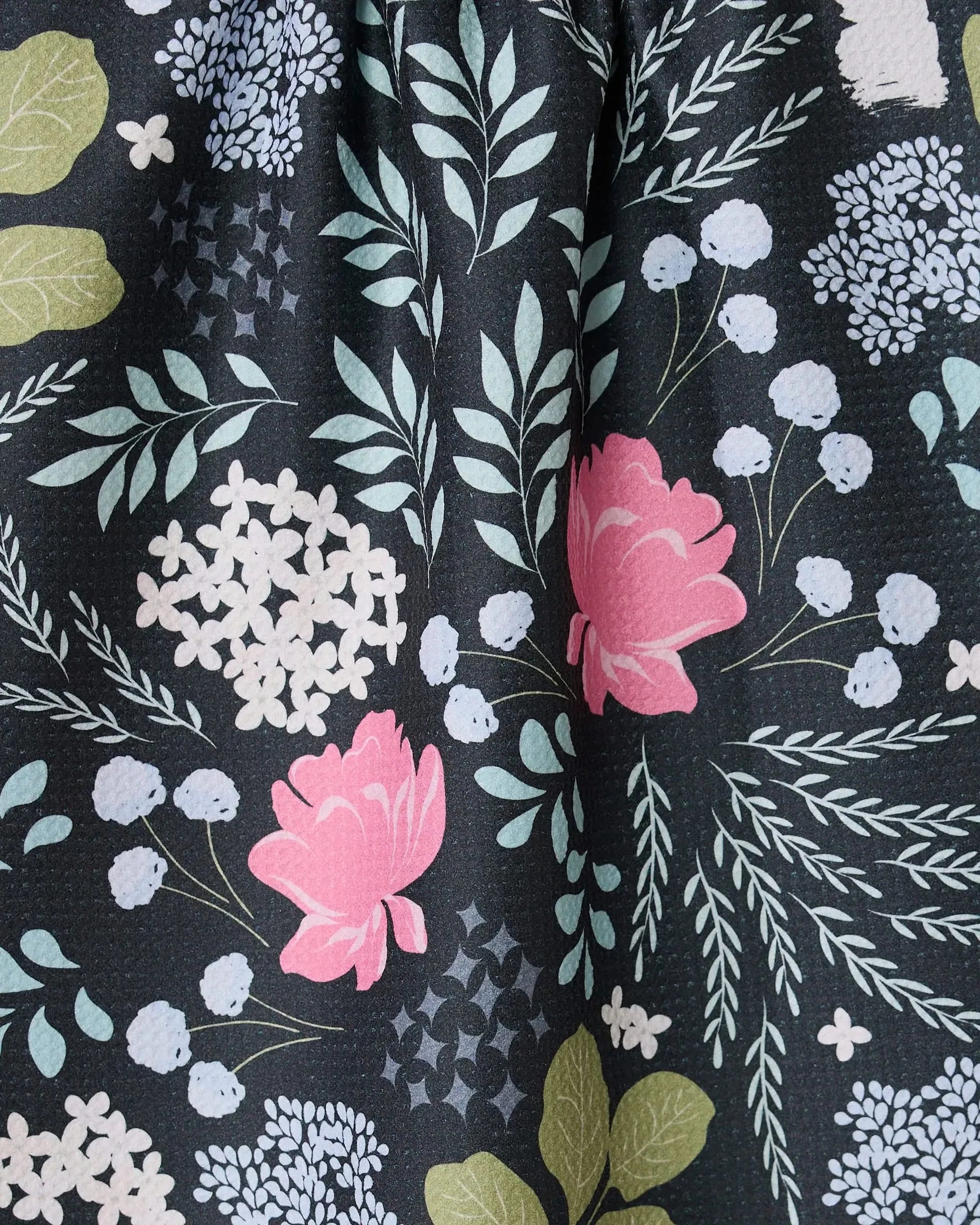 Close-up of floral fabric with pink flowers and green leaves on a dark background