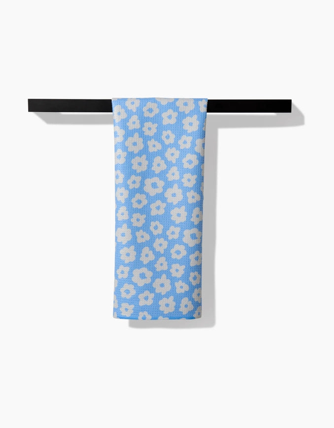 Blue floral towel hanging on a black rack against a white background