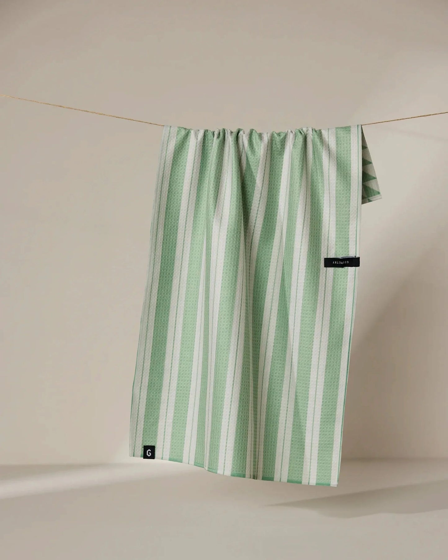 Green and white striped skirt hanging on a line against a beige background