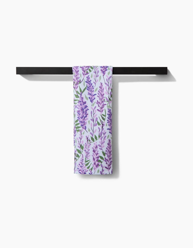 Towel with purple floral pattern hanging on a black towel rack against a white background