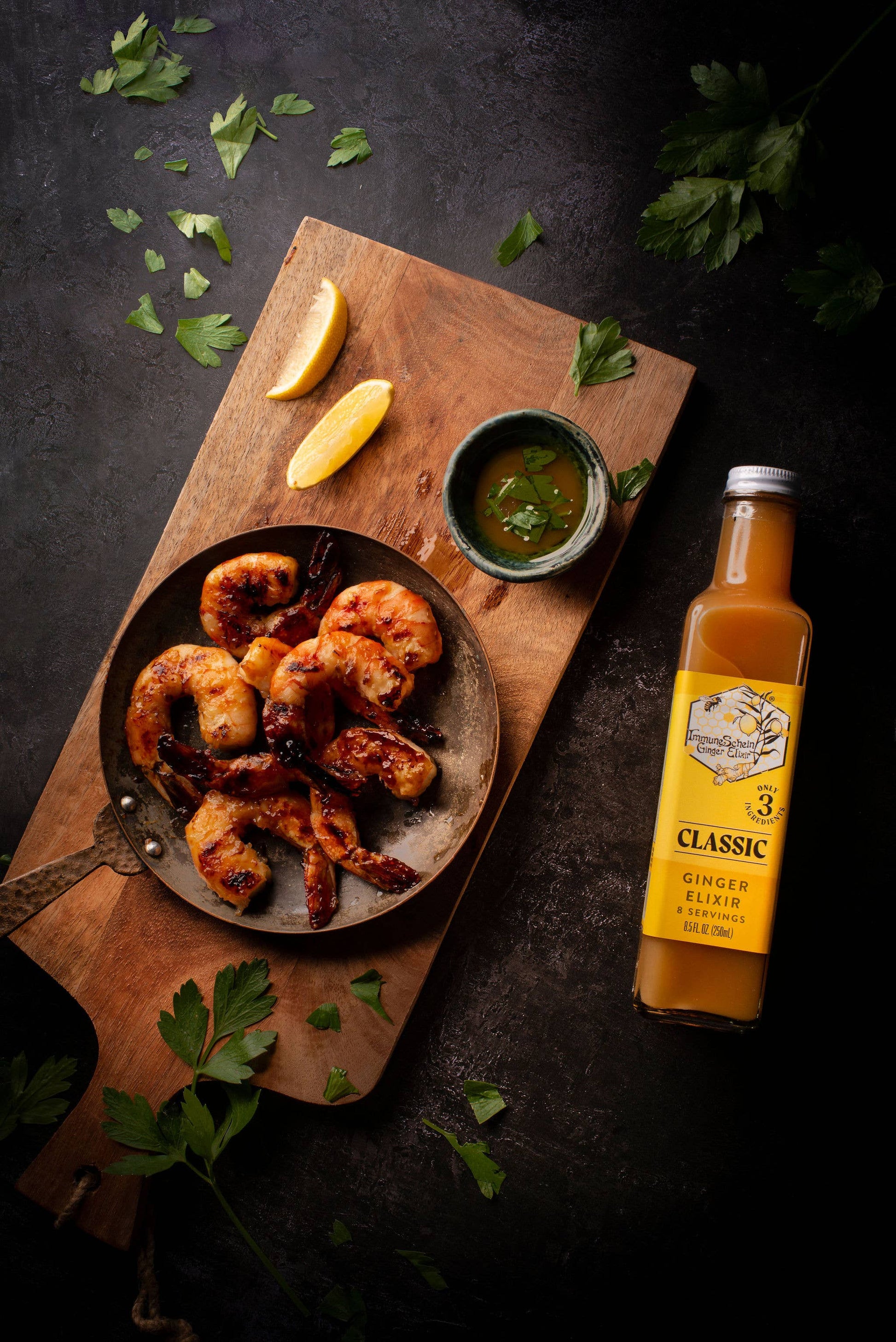 Garnished dish of fried food on a wooden board with a bottle of ginger beer.