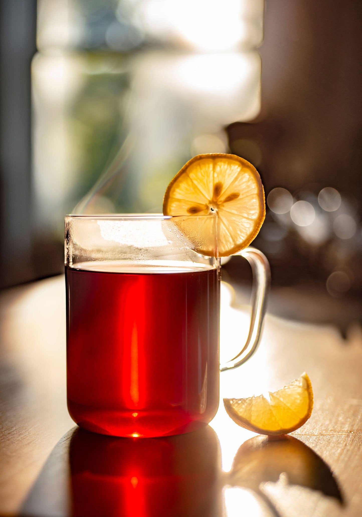 Glass mug with red liquid and lemon slice on a wooden surface