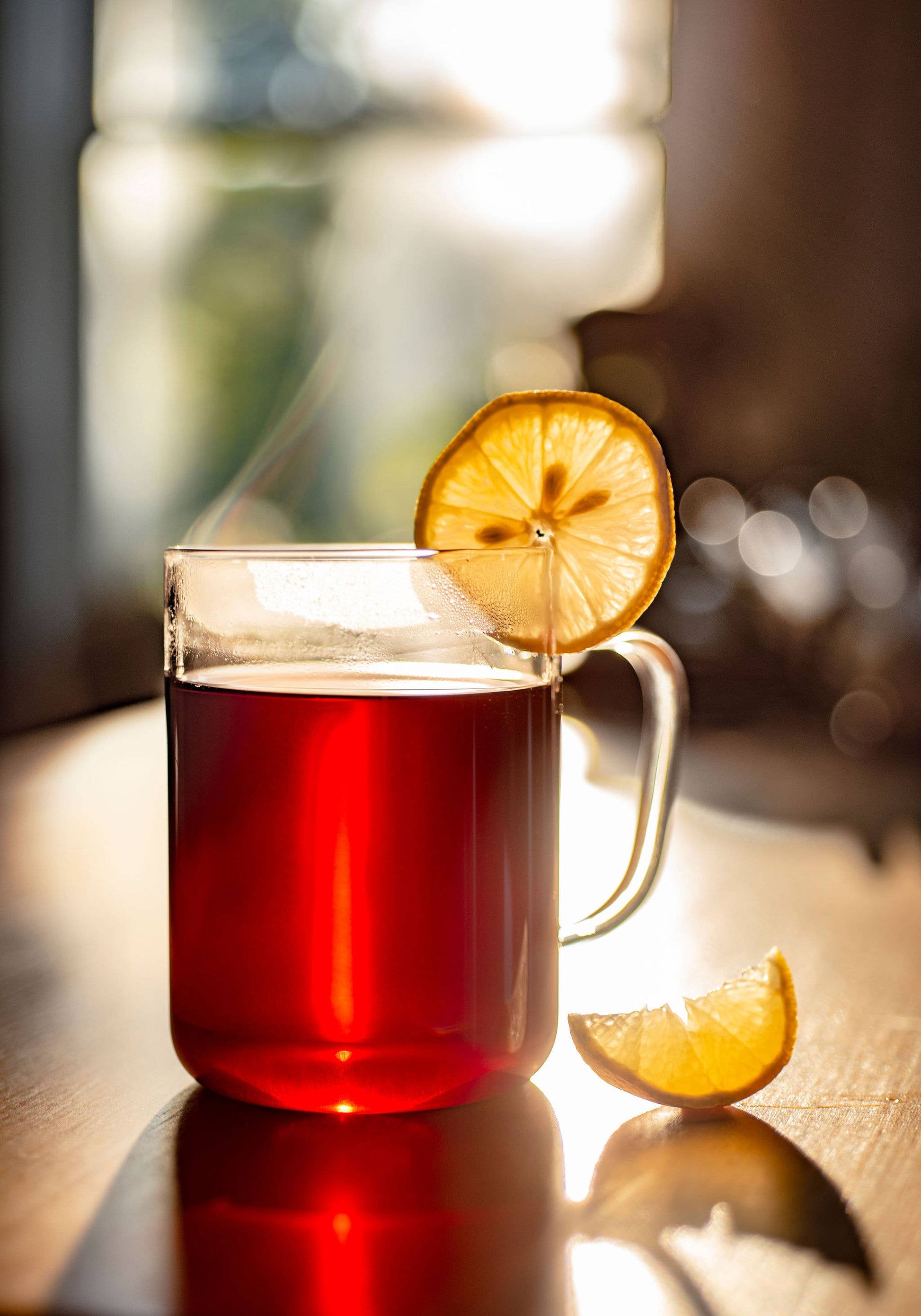 Glass mug with red liquid and lemon slice on a wooden surface