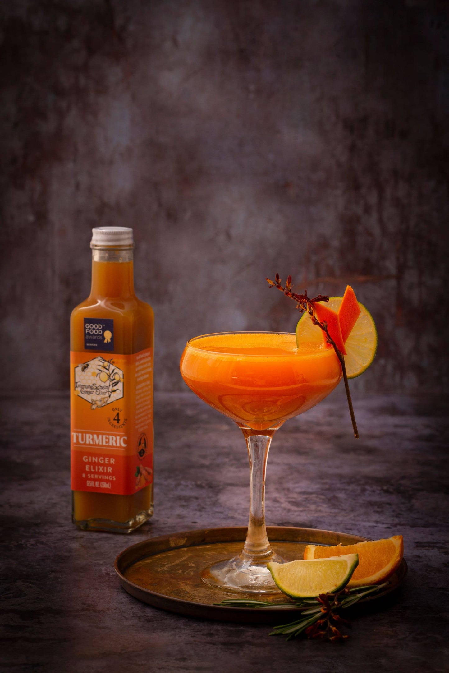 Cocktail with a bottle of Turmeric Ginger Liqueur on a dark background