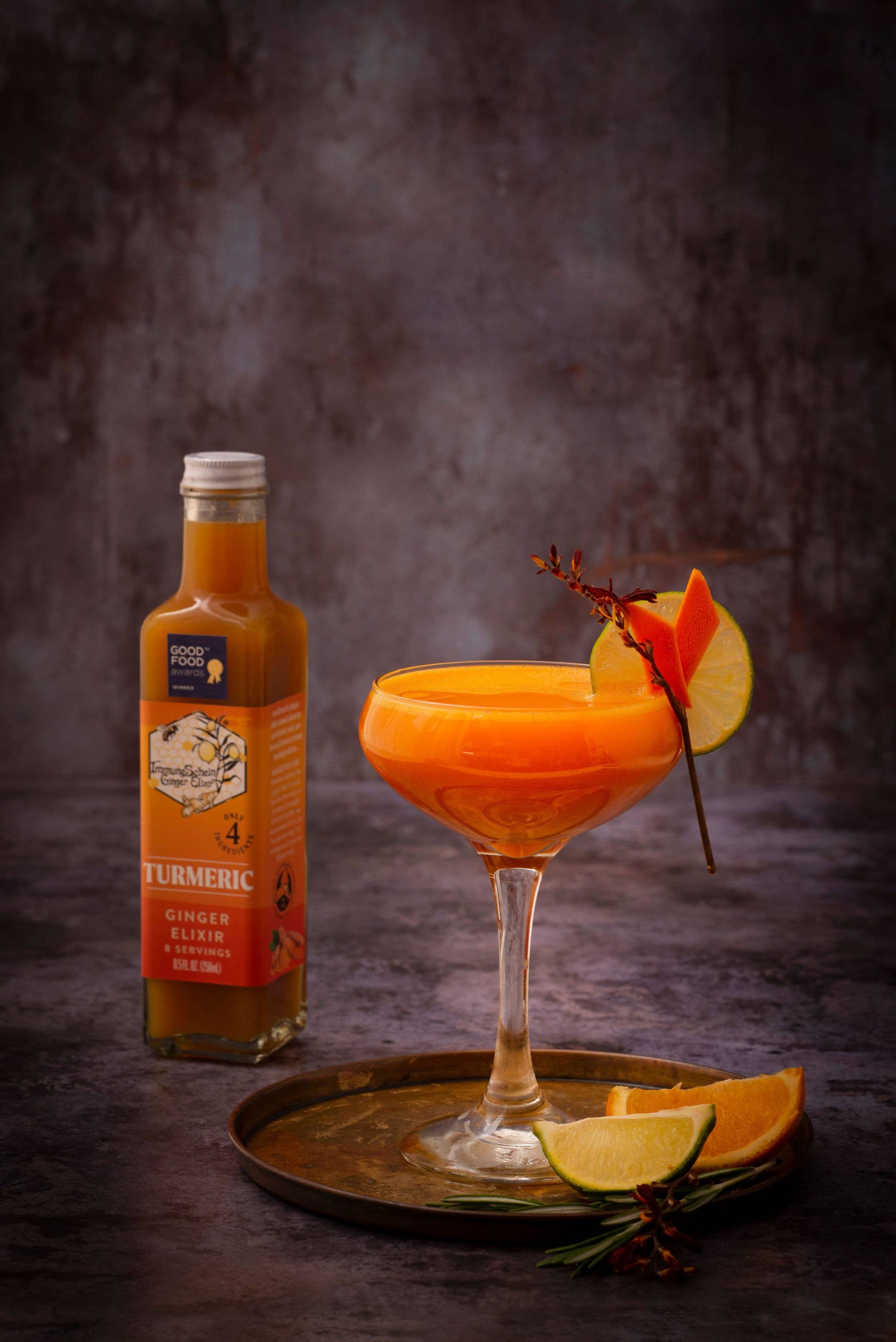 Cocktail with a bottle of Turmeric Ginger Liqueur on a dark background