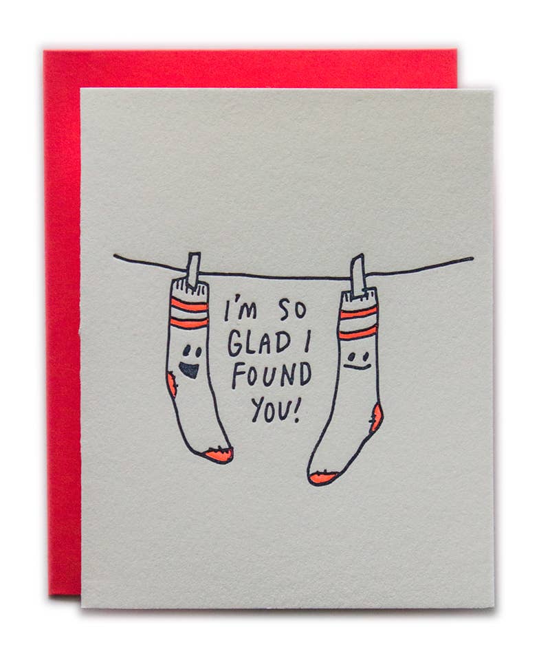 Card with socks on a clothesline and text 'I'm so glad I found you!' against a red and gray background.