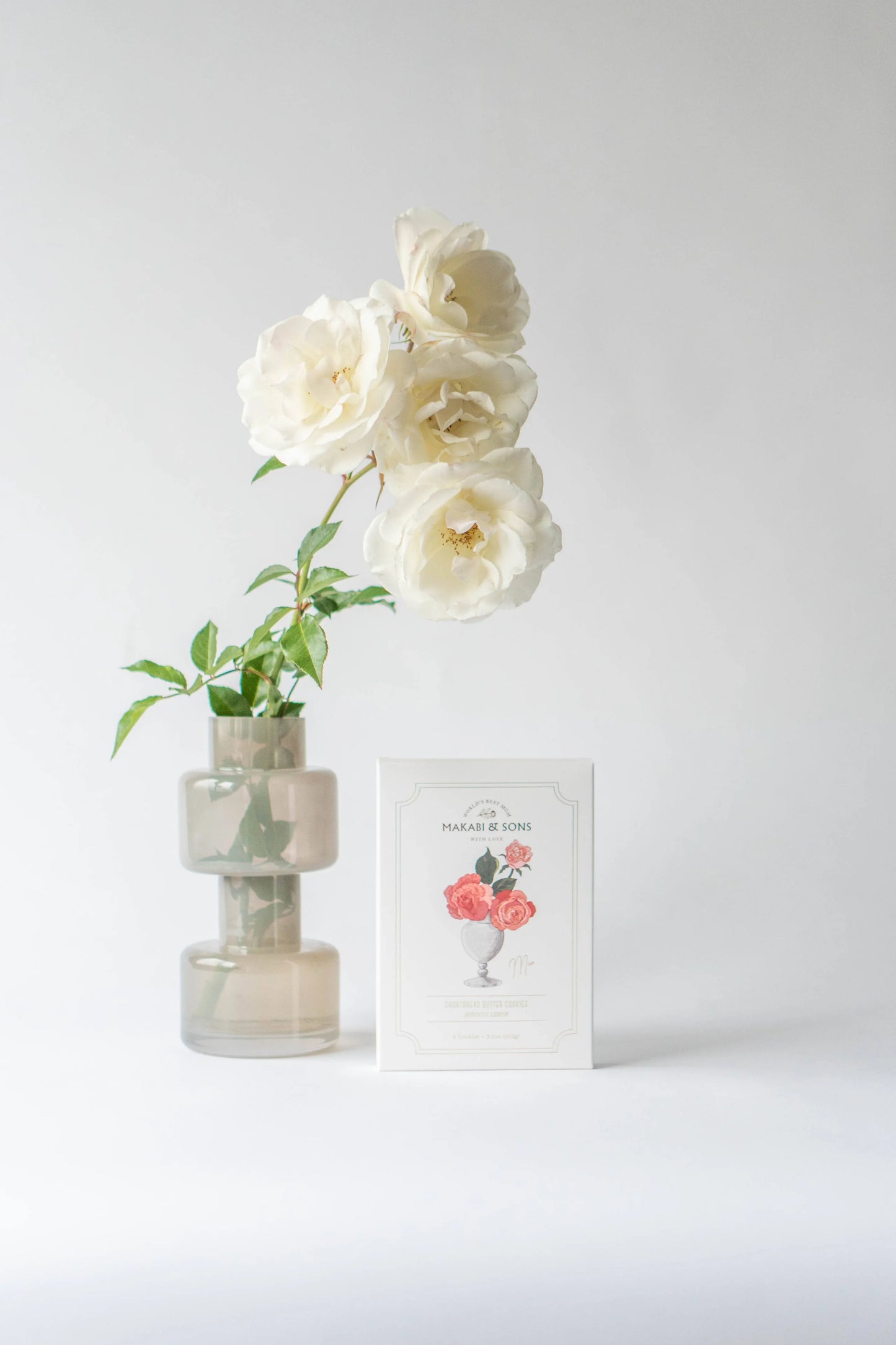 White flowers in a vase with a framed picture on a light gray background