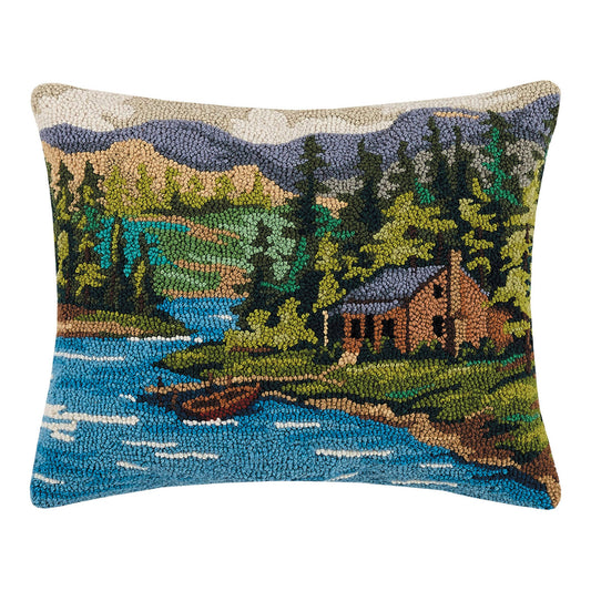Decorative pillow with a nature scene featuring a cabin by a lake.